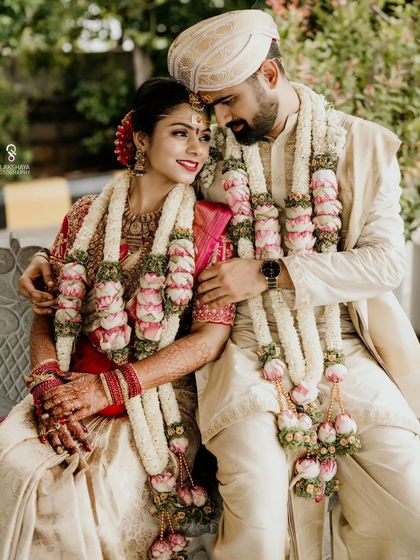 A classic portrait of the couple seated on a bench, sharing a quiet moment on their wedding day.