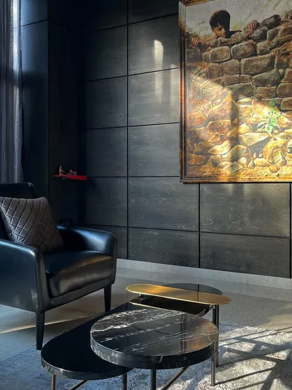 A quiet corner in an office we designed, demonstrating the power of chiaroscuro. We used a palette of dark, textured panels and leather, allowing natural light to carve out the space and highlight the artwork, creating a sophisticated and focused atmosphere.