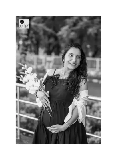 A beautiful black and white portrait of the mother-to-be, highlighting her happy expression and the gentle way she holds her baby bump.