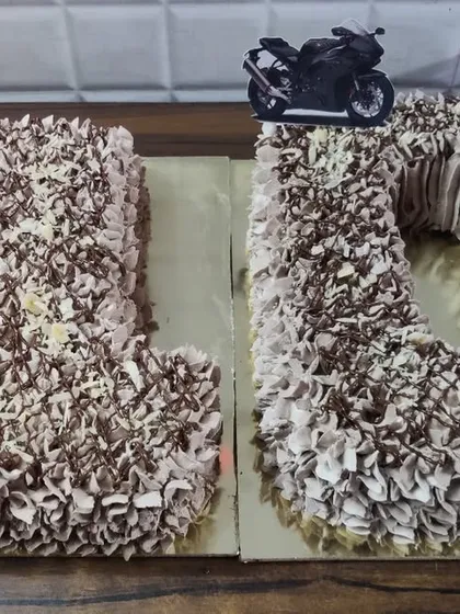 A number cake for a 20th birthday. This chocolate cake is shaped into the numbers '2' and '0' and topped with a motorcycle accent.