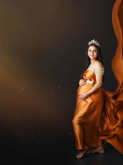 Bathed in a divine light, this portrait captures the mom-to-be as a true princess. The flowing orange gown and pearl details add to the magical and regal atmosphere of the shot.
