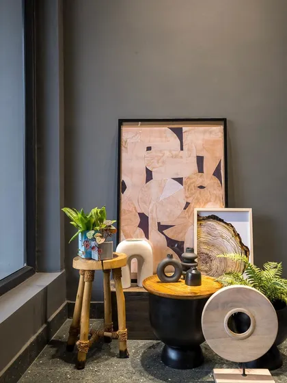 The interplay of natural wood, black ceramic, and abstract art creates a sophisticated and modern corner.