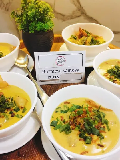 Samosa with a twist! Our Burmese Samosa Curry features crispy samosas floating in a rich, fragrant, and creamy coconut-based curry, garnished with fresh herbs.