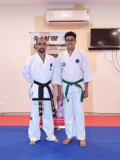 Standing with a student who has just earned his green belt. His progress is a great example for others in the academy.