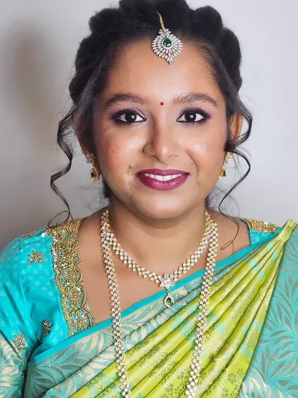 A smiling shot of Jebha during her engagement, looking happy and radiant in her blue and green saree.