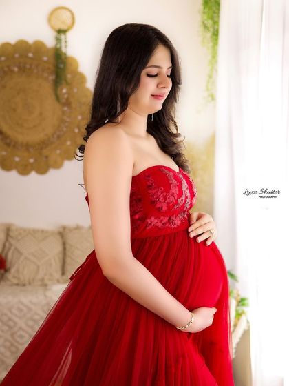 A profile shot by the window, using natural light to create a soft and beautiful portrait. The red tulle gown adds a touch of romance and elegance.