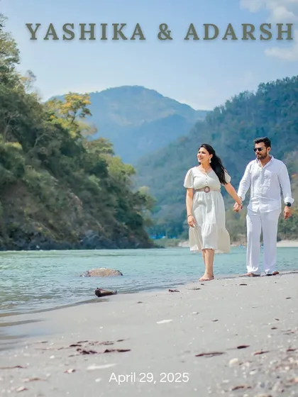 A beautiful save-the-date photo of a couple walking along the sandy banks of the Ganga in Rishikesh, dressed in elegant white.
