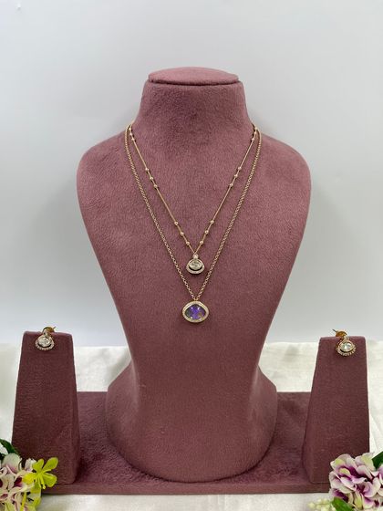 The Kritika Dual Shine Necklace Set. This delicate piece features two layered chains with unique, color-shifting stones, available in purple, green, and white.