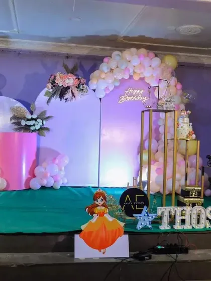 Here is a full view of the stage we decorated for Thoshini's first birthday. We used a soft pastel color palette with pink and peach balloons, floral arrangements, and a custom name display to create a dreamy princess theme.