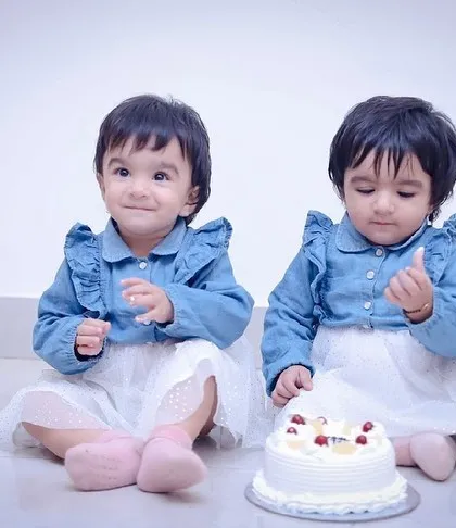 Two happy one-year-olds enjoying their shared birthday treat. We specialize in capturing the joy of milestone celebrations for the whole family.