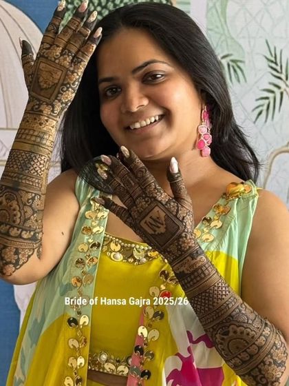 A beautiful shot of the bride showing off her full-arm mehendi. Her happy and confident pose highlights the detailed work on both the front and back of her hands.