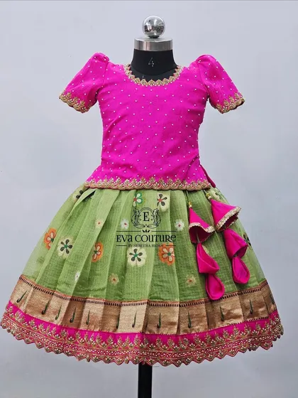 A Zari Kota lehenga with a green floral skirt and a pink blouse. The skirt has a scalloped, embroidered hem.