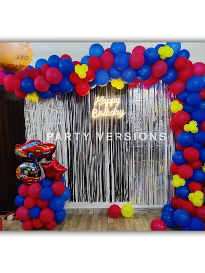 A fun and simple Car-themed balloon decoration for a birthday at home. The red, blue, and yellow balloon arch is accented with a Lightning McQueen foil balloon.