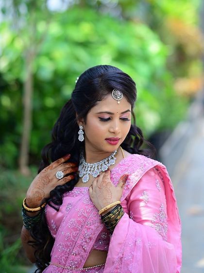 A soft and romantic reception look for Tejeshwini. Her pink lehenga is paired with glowing makeup and soft curls for an ethereal, princess-like feel.