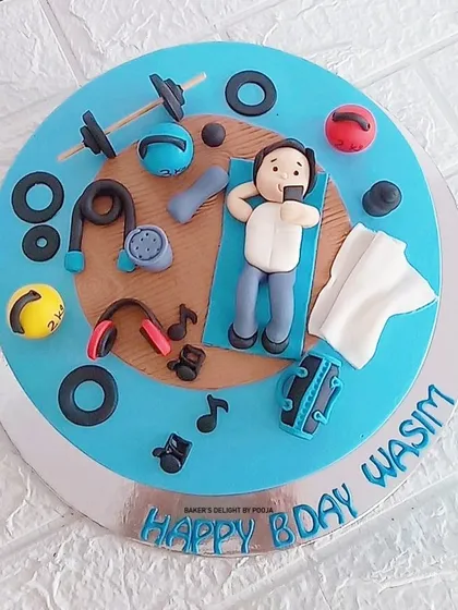 A cake for a true fitness enthusiast. This design features a fondant figure relaxing at the gym after a workout, surrounded by edible weights, kettlebells, headphones, and other gym equipment.