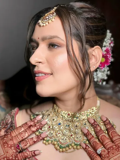 A side profile of this lovely bride shows the soft tendrils framing her face and the floral arrangement in her hair. The makeup highlights her features with a natural, dewy finish.