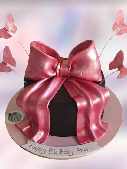 A gift box cake with a large, shiny pink bow. The butterflies add a touch of whimsy to this elegant design.