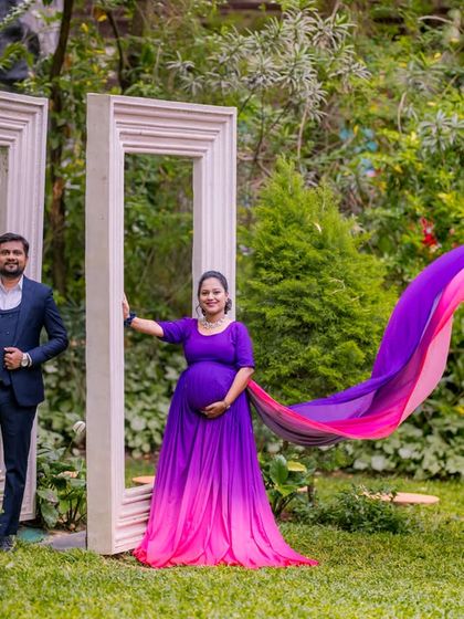 A maternity portrait using the oversized white photo frames in the garden for a creative and unique composition.