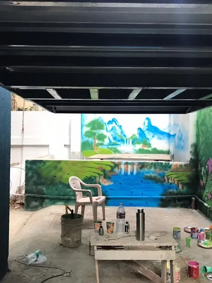 An in-progress view of the outdoor mural project, showing the different landscape sections being painted.