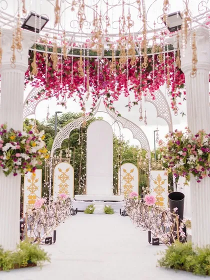 The view looking down the aisle through the floral archway. The path is lined with flowers, leading to a beautifully decorated stage, creating a grand sense of arrival.