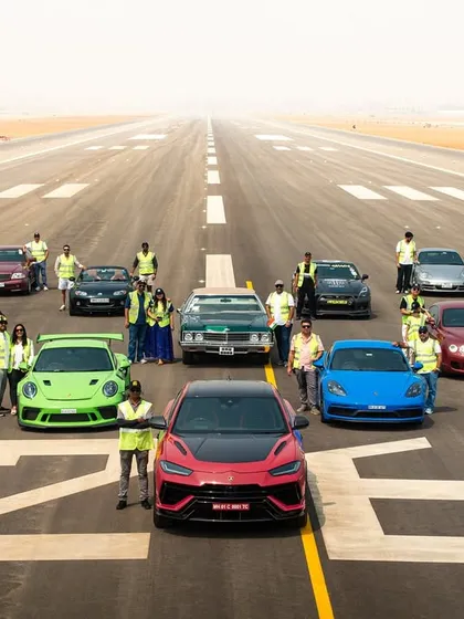 A behind-the-scenes look at a large automotive event, showing the coordination required to arrange both the cars and the crew for a group photograph.