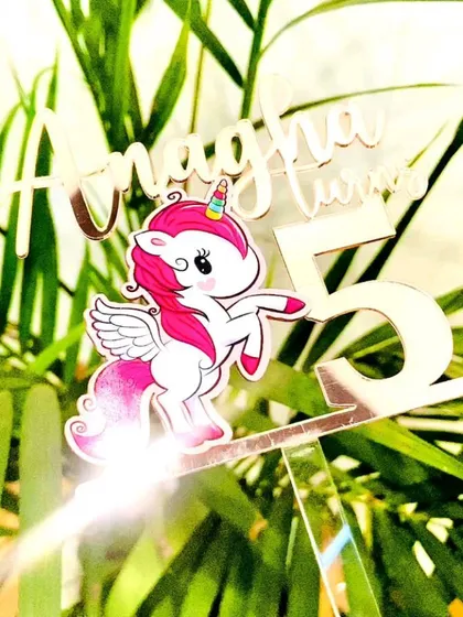 A close-up of the "Anagha turns 5" unicorn topper, focusing on the magical details and the sparkle of the rose gold finish.