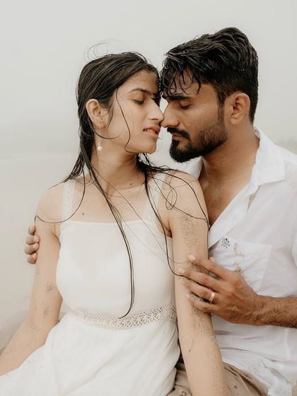 An intimate close-up on the wet sand. This portrait captures the raw emotion and deep connection between the couple, with the rain adding to the romantic atmosphere.