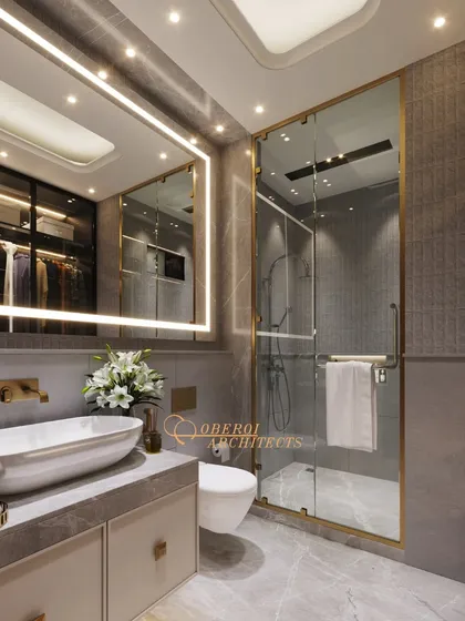 The gold-finished frame of the shower enclosure and the matching fixtures add a touch of glamour to the space.