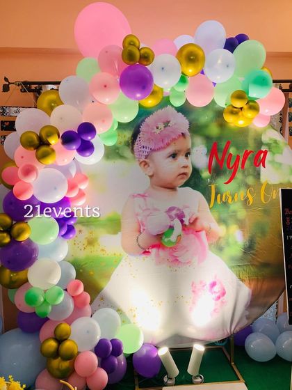A sweet and simple setup featuring a large photo of the birthday girl, framed by a colorful balloon arch.
