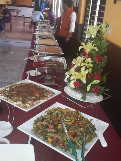 A long shot of a buffet table featuring a variety of salads and hot dishes. The floral arrangement adds a touch of elegance to the overall presentation.