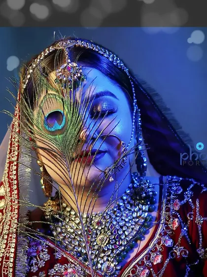 An artistic bridal portrait using a peacock feather. This creative shot with dramatic blue lighting is perfect for a bride who wants something unique and memorable.