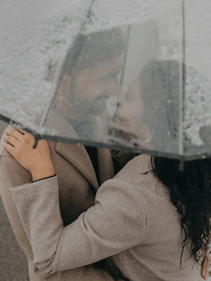 A close, intimate moment shared under an umbrella in the falling snow. This pre-wedding photo from Kazakhstan focuses on the couple's connection, protected from the elements.