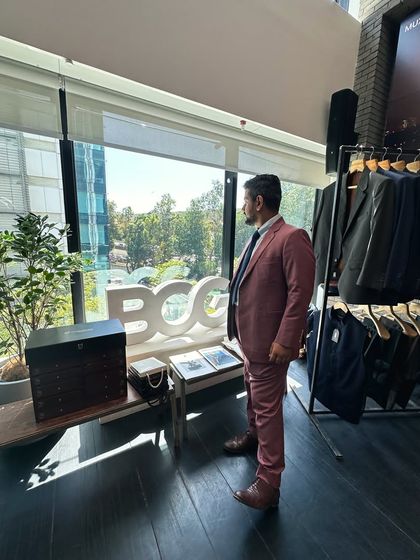 Our founder takes a moment at the BCG trunk show, surrounded by the tools of our trade. The setup, with racks of suits and the iconic BCG logo, highlights the seamless integration of our bespoke service into the corporate world.