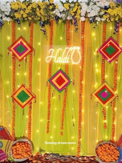 A bright and cheerful Haldi backdrop featuring a neon sign, fairy lights, and colorful Gujarati-style mirror work hangings against a lime-green drape.