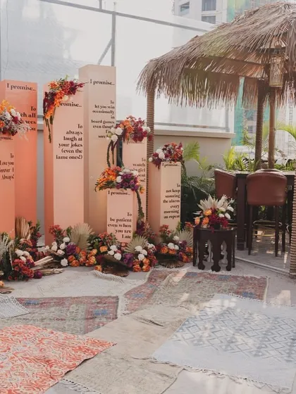 Our unique 'Promise Pillars' photobooth, set against a backdrop of boho rugs and a thatched-roof hut, creating a relaxed, festival-like atmosphere.