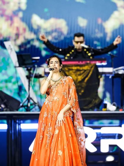 Jonita Gandhi performing, with A.R. Rahman visible at the keyboard in the background. This image shows the multi-layered nature of our stage design, allowing for simultaneous artist features.