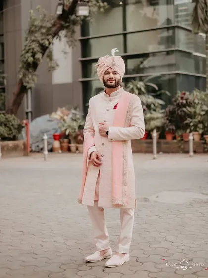 A full-length portrait of the groom looking sharp in his pastel pink sherwani. This shot shows off his complete wedding day look with elegance and style.