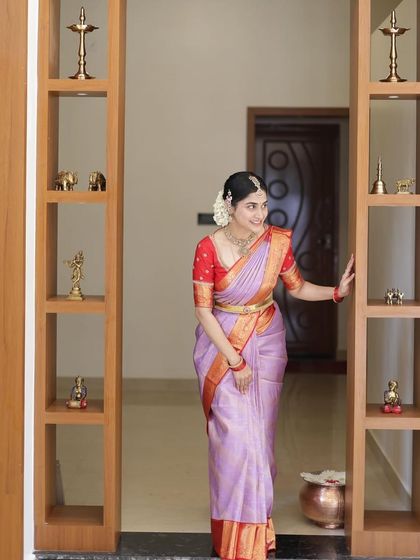 A full-length shot of the bride in her lavender and red ensemble, framed by a modern wooden doorway.