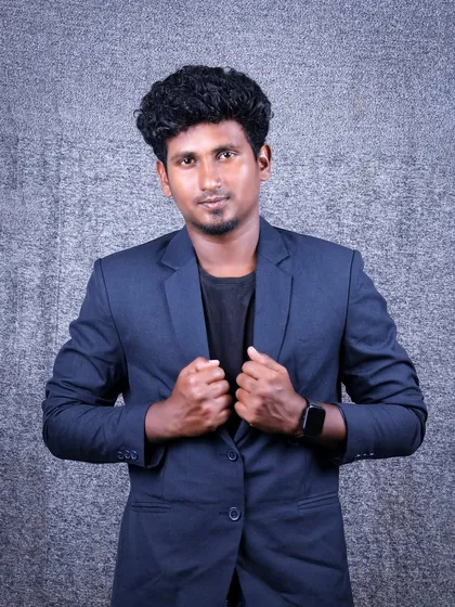 A portrait showing a strong and confident stance. The subject is adjusting his blazer, which creates a dynamic and engaging image suitable for a professional profile.