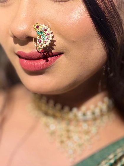 A close-up of a beautiful peacock design nath, worn by a model.