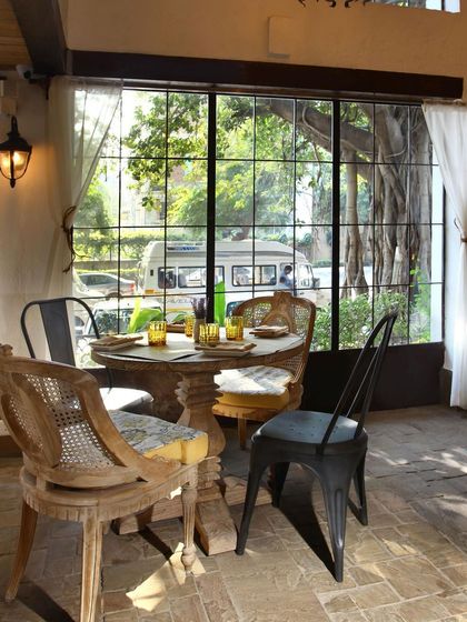 A cozy table for four at Amour Bistro, set against a large window with views of the trees outside. The design prioritizes creating intimate and comfortable dining spots within the larger space.