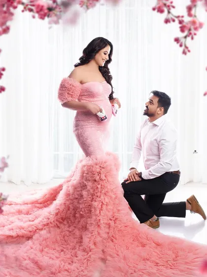 A romantic and fairytale-like couple portrait. The dad-to-be kneels before his partner, who is stunning in a pink ruffled gown, creating a truly magical scene.
