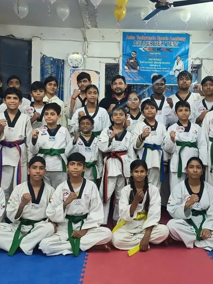 The team poses together after the belt distribution ceremony, a mix of yellow, green, and blue belts showing the different stages of progress.