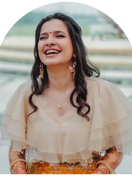 A joyful, candid moment highlighting the delicate, multi-layered organza cape blouse. The pearl drop detailing along the edges adds a subtle touch of elegance.