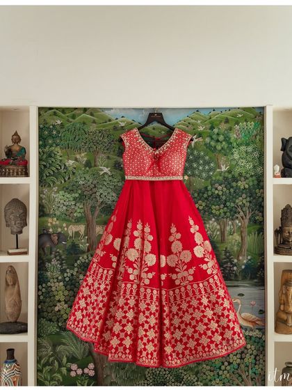 A beautiful shot of the bride's red lehenga against an artistic, hand-painted wall. This photo highlights the beauty of the outfit and the unique decor of the getting-ready location.