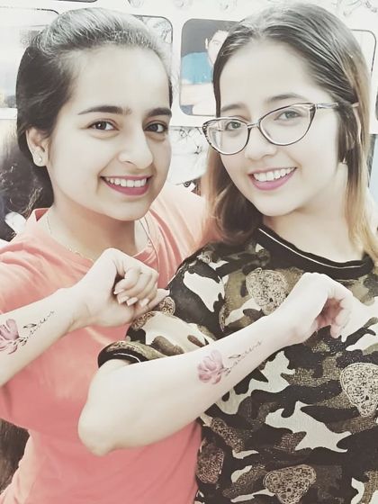 Friends with matching watercolor lotus flower tattoos on their forearms.