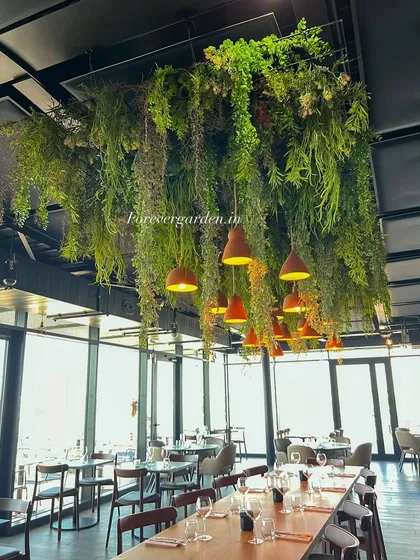 A custom-designed hanging foliage installation transforms the ceiling of this restaurant, creating an immersive, garden-like dining experience that enhances the decor.