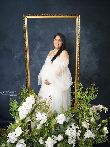 A beautifully framed solo portrait. The golden frame and white floral arrangement create an artistic and elegant composition.