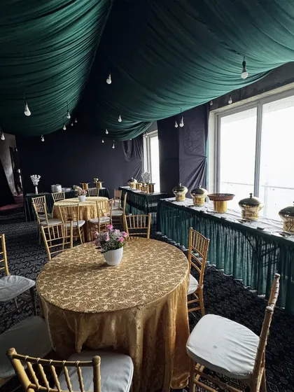 Another angle of our green and gold themed event setup, showing the overall layout of the dining area and buffet line. We ensure the entire space feels cohesive and well-planned.