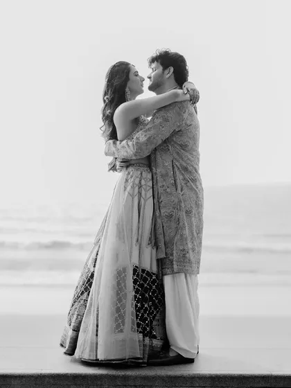 A timeless black and white photo of Rupanshi and Yash embracing by the sea. The simplicity of the composition focuses all the attention on their connection.